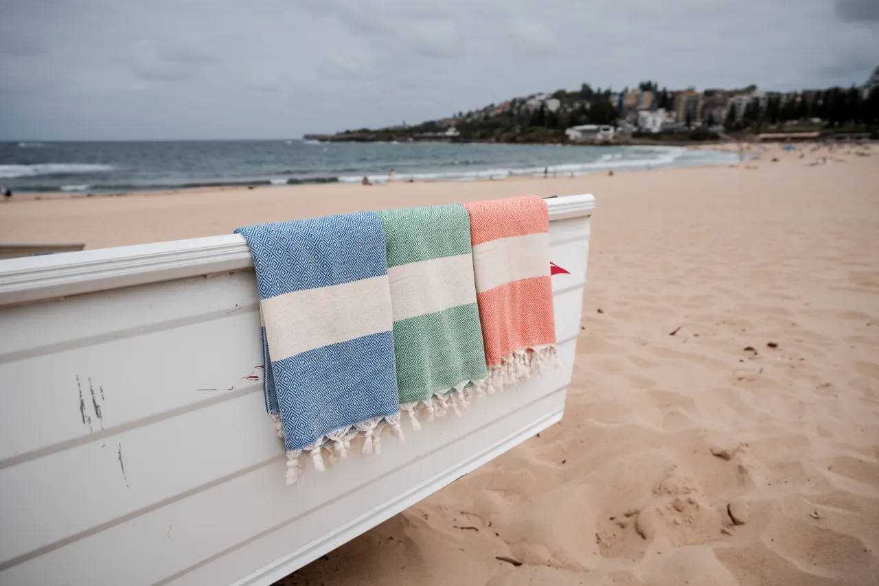 Colourful foutas draped over a beach boat on the sand